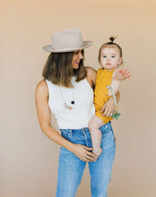 Load image into Gallery viewer, Mom with hat wearing The Audrey Chewable silicone necklace in five colors tan brown green gray pink white black with satin string for teething baby