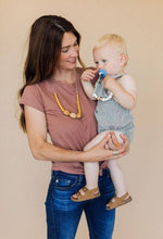 Load image into Gallery viewer, close up of mom wearing The Austin Chewable silicone necklace in two colors tan brown mustard yellow with satin string for teething baby