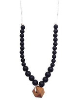 Load image into Gallery viewer, close up of The Collins Chewable silicone necklace in two colors tan brown wooden geometric charm black pearl beads with satin string for teething baby