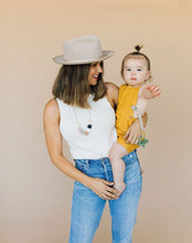 Load image into Gallery viewer, Mom with hat wearing The Audrey Chewable silicone necklace in five colors tan brown green gray pink white black with satin string for teething baby 
