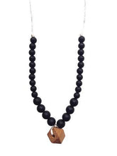 Load image into Gallery viewer, close up of The Collins Chewable silicone necklace in two colors tan brown wooden geometric charm black pearl beads with satin string for teething baby 
